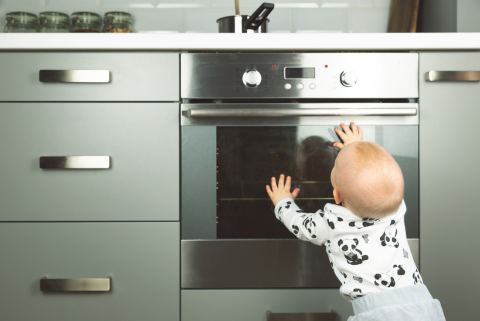 Baby leaning on oven